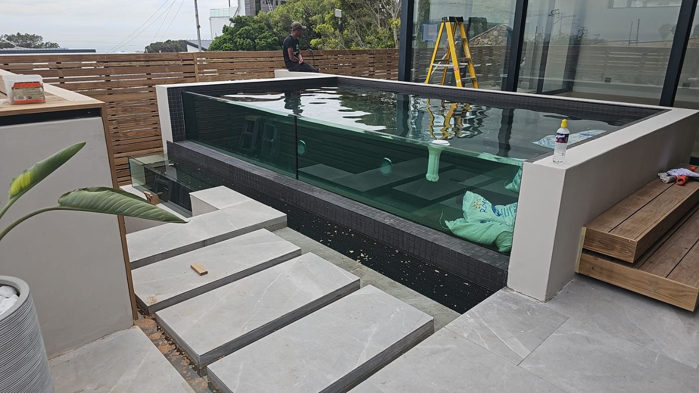 Glass-walled pool under construction with sea view