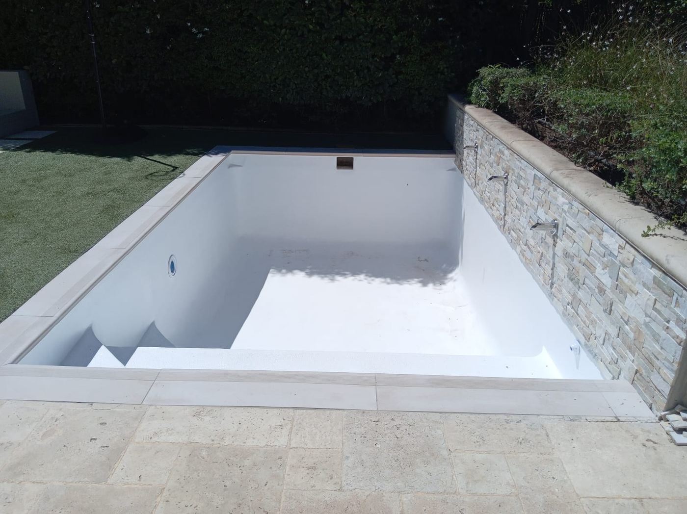 Freshly finished marbelite pool with a stone feature wall