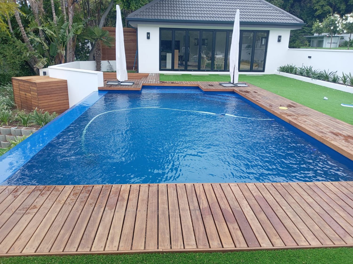 Navy blue pool with timber deck and umbrellas