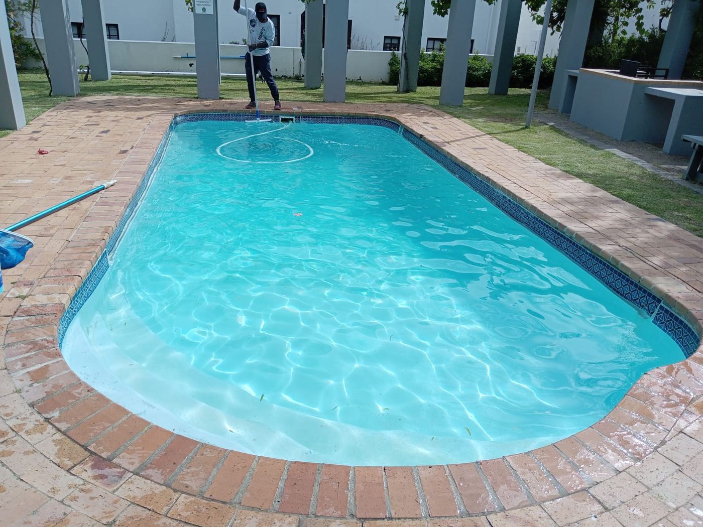 Pool Crew technician cleaning a complex swimming pool
